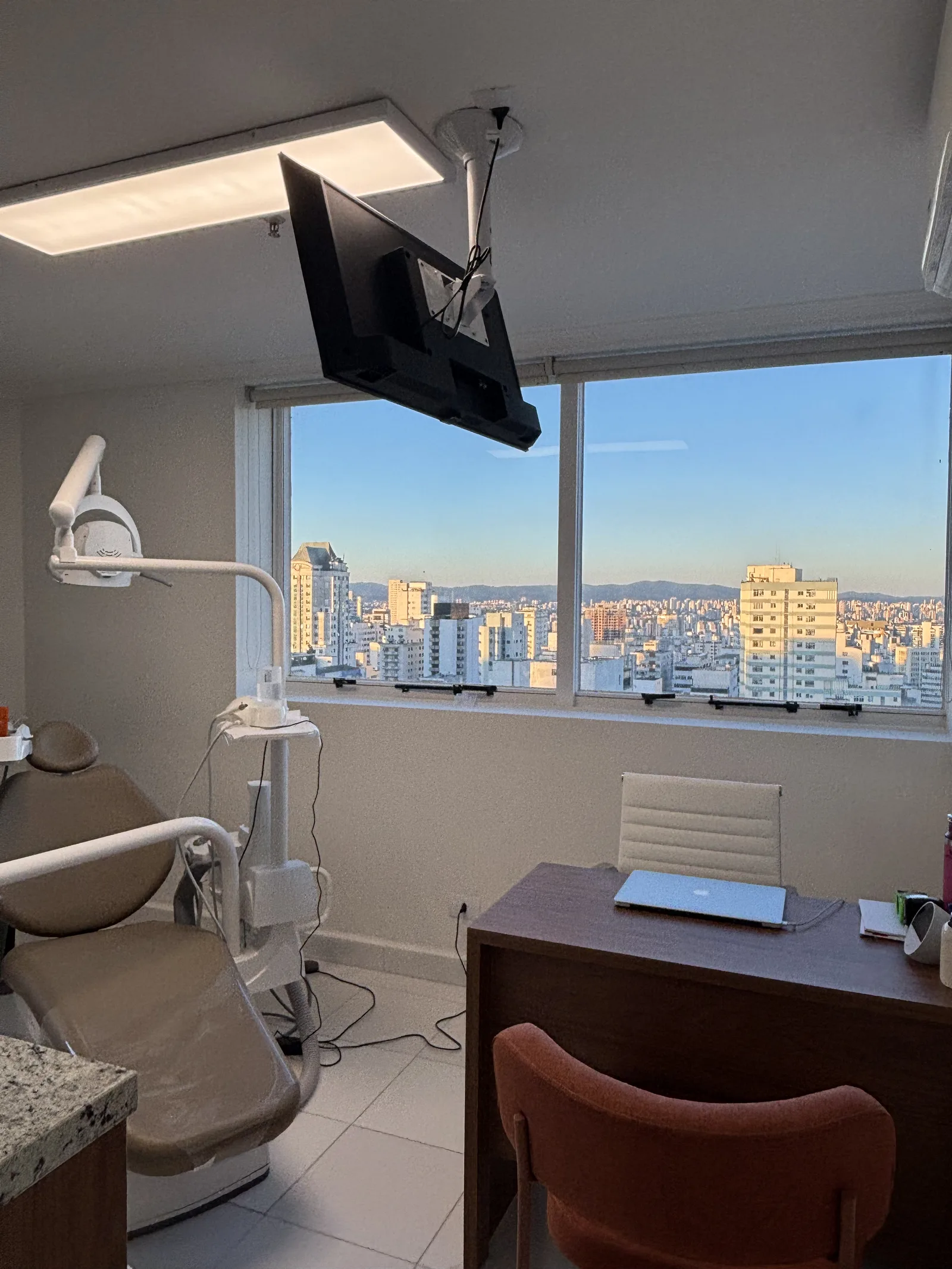 Sala odontológica em andar alto com janela ampla e vista livre